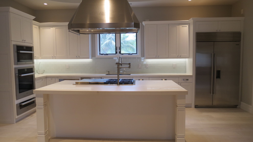 Inspiration for a large transitional l-shaped light wood floor and beige floor enclosed kitchen remodel with a double-bowl sink, shaker cabinets, white cabinets, marble countertops, blue backsplash, glass tile backsplash, stainless steel appliances and an island