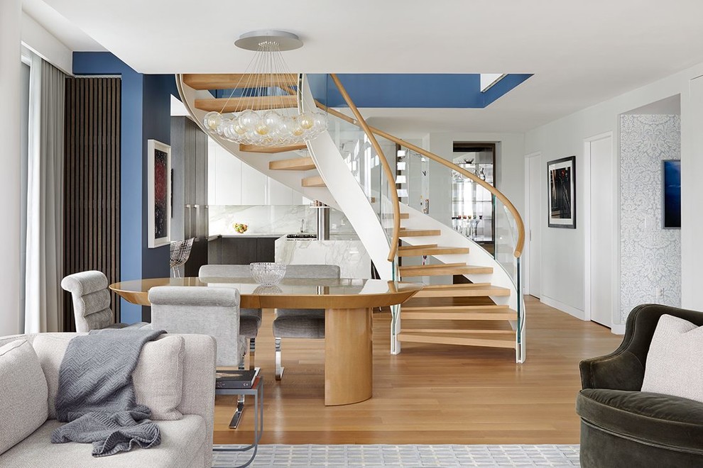 Photo of an expansive contemporary wood curved staircase in San Francisco with glass railing and open risers.