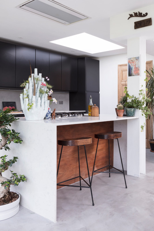 Photo of a large eclectic eat-in kitchen in Edinburgh with an integrated sink, flat-panel cabinets, black cabinets, quartzite benchtops, grey splashback, panelled appliances, concrete floors, with island, grey floor, white benchtop and cement tile splashback.