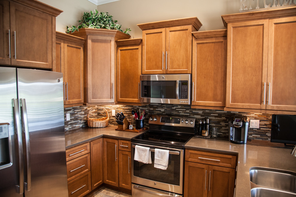 Mid-sized u-shaped ceramic tile and vaulted ceiling kitchen photo with an undermount sink, shaker cabinets, brown cabinets, wood countertops, mosaic tile backsplash, stainless steel appliances and brown countertops