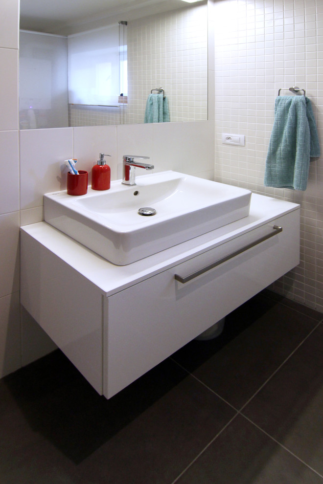This is an example of a small modern master bathroom in Other with flat-panel cabinets, white cabinets, laminate benchtops, an alcove shower, a one-piece toilet, white tile, ceramic tile, white walls and ceramic floors.