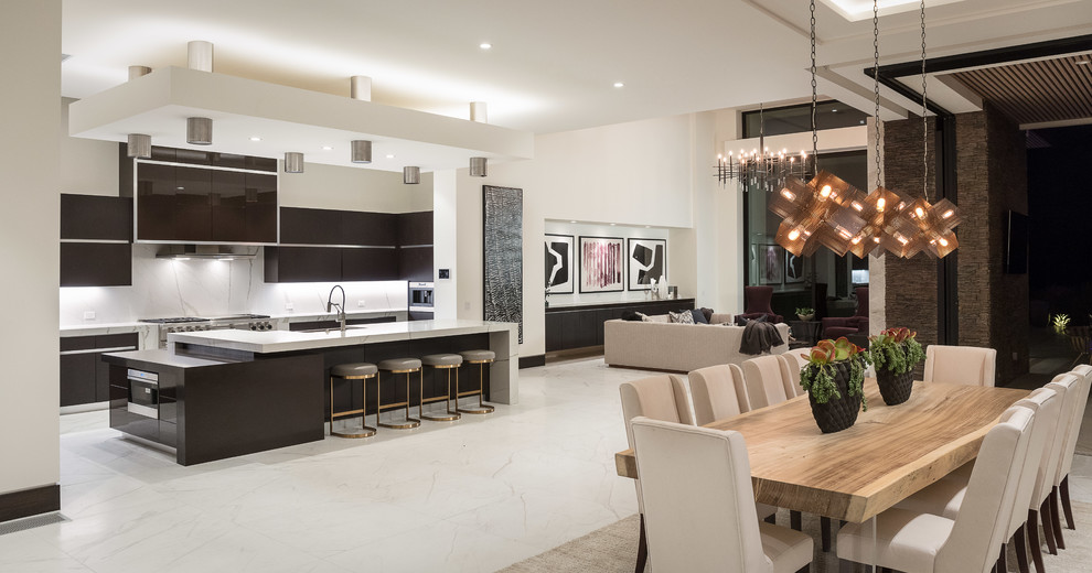 Inspiration for a contemporary galley open plan kitchen in Orange County with flat-panel cabinets, dark wood cabinets, white splashback, stone slab splashback, stainless steel appliances, with island, white floor and white benchtop.