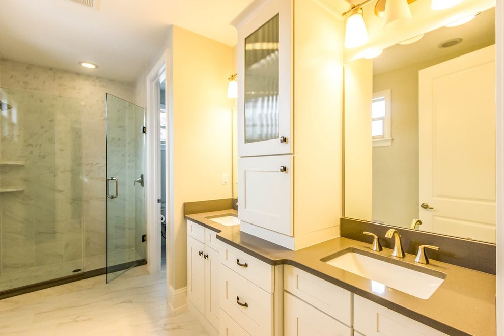 This is an example of a large contemporary master bathroom in Orlando with glass-front cabinets, white cabinets, white walls, marble floors, an alcove shower, an undermount sink, solid surface benchtops, beige floor and a hinged shower door.