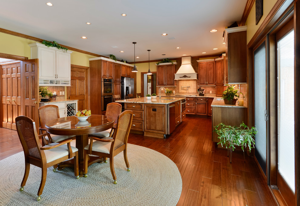 Large transitional u-shaped medium tone wood floor eat-in kitchen photo with beaded inset cabinets, medium tone wood cabinets, granite countertops, beige backsplash, mosaic tile backsplash, stainless steel appliances and an island