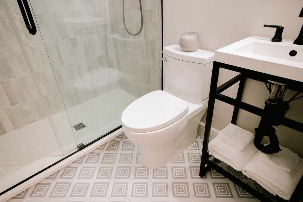 Пример оригинального дизайна: маленькая ванная комната в морском стиле с черными фасадами, душем в нише, унитазом-моноблоком, белыми стенами, полом из керамогранита, душевой кабиной, столешницей из искусственного кварца, синим полом, душем с распашными дверями, белой столешницей, нишей, тумбой под одну раковину и напольной тумбой для на участке и в саду