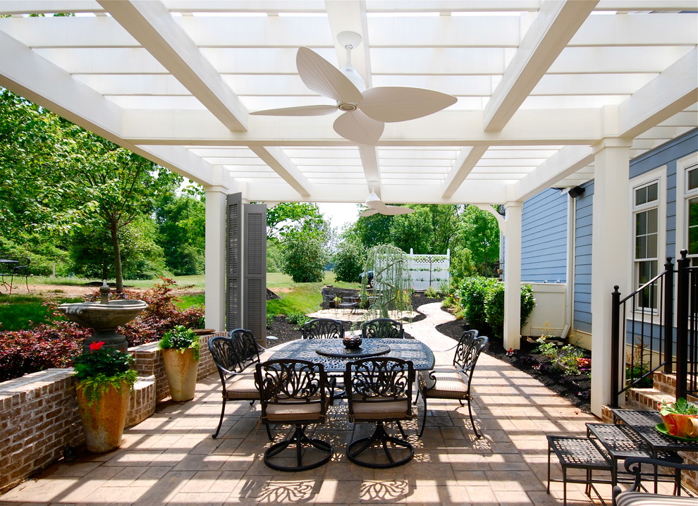 This is an example of a mid-sized traditional courtyard patio in Other with a pergola, a water feature and brick pavers.