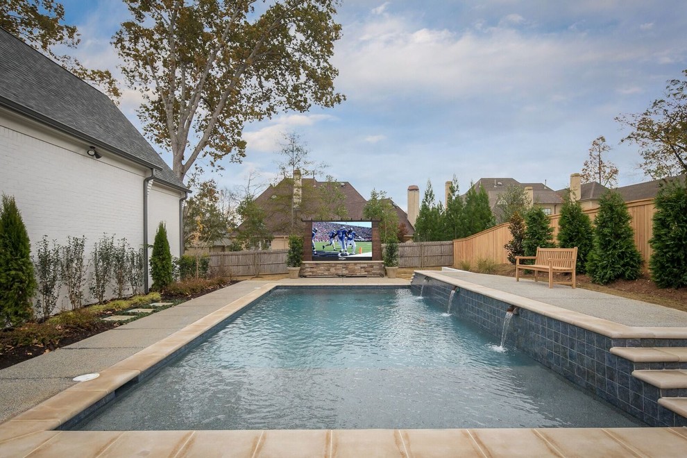 This is an example of a mid-sized transitional backyard rectangular pool in Other with a water feature and concrete slab.