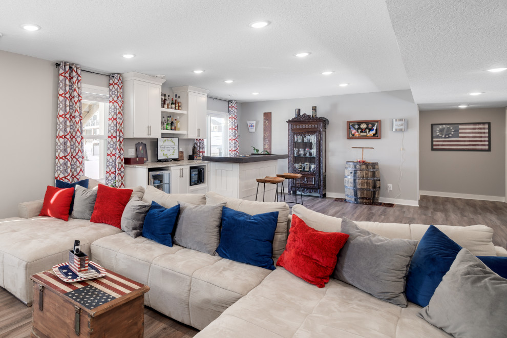 This is an example of a large traditional walk-out basement in Other with a home bar, grey walls, vinyl flooring and brown floors.