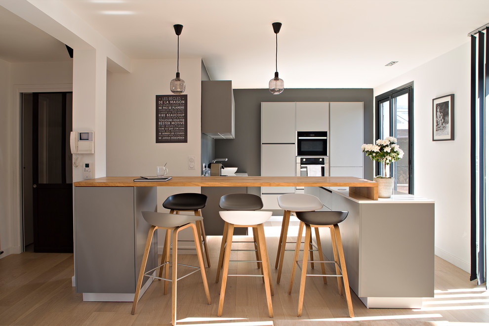 This is an example of a mid-sized contemporary open plan kitchen in Rennes with quartzite benchtops, with island, white benchtop, flat-panel cabinets, grey cabinets and beige floor.