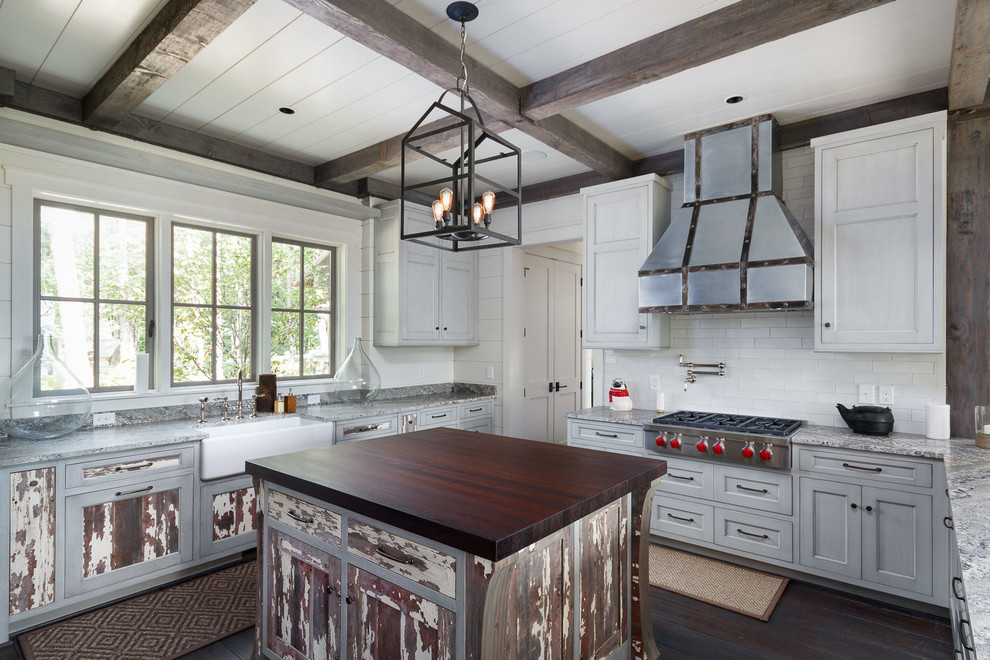Mid-sized transitional kitchen in Charlotte with a farmhouse sink, recessed-panel cabinets, granite benchtops, white splashback, stainless steel appliances, dark hardwood floors, with island and distressed cabinets.