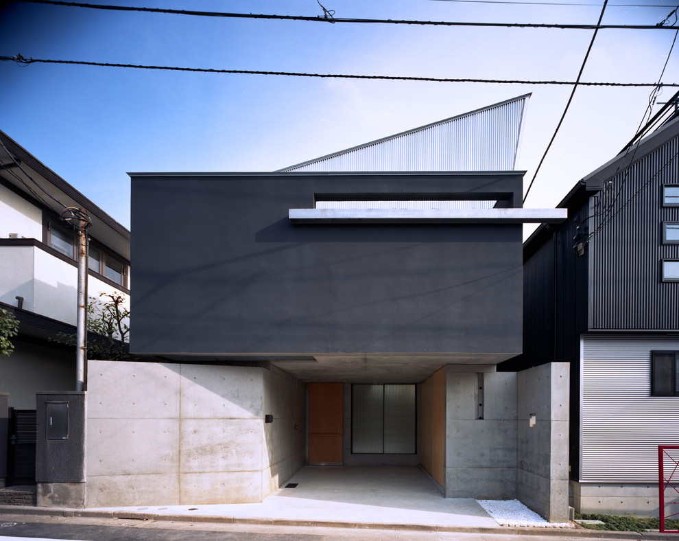 Mid-sized modern two-storey stucco black house exterior in Tokyo with a shed roof and a metal roof.