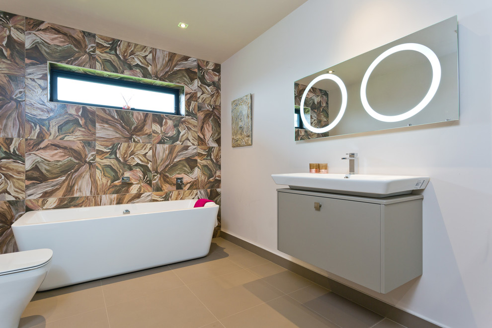 Design ideas for a large modern kids bathroom in Belfast with grey cabinets, a freestanding tub, a corner shower, a one-piece toilet, multi-coloured tile, porcelain tile, porcelain floors and a wall-mount sink.