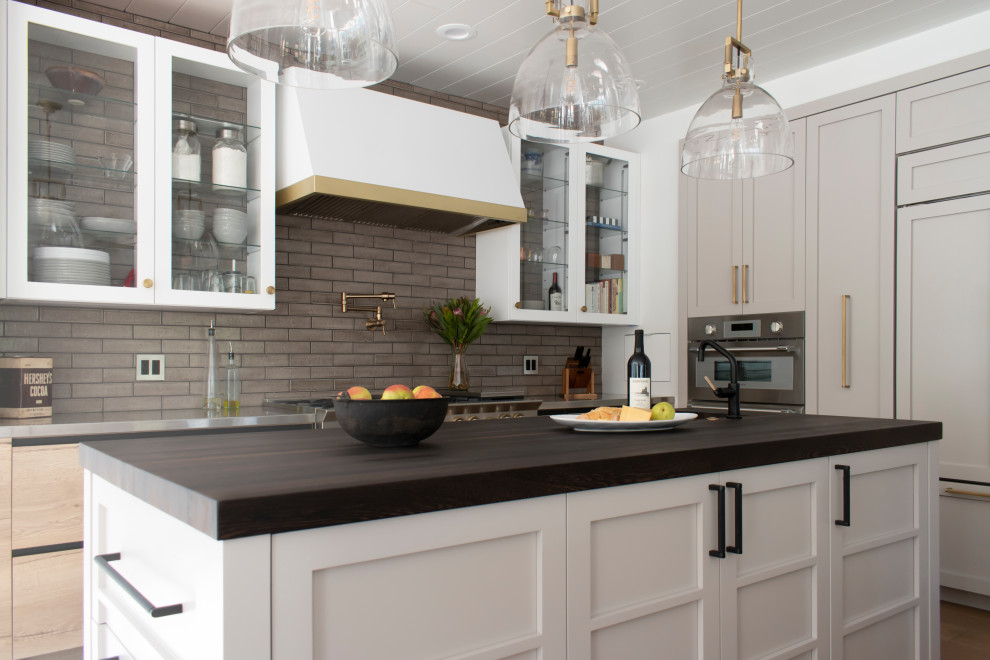 Open concept kitchen - mid-sized rustic l-shaped light wood floor, beige floor and wood ceiling open concept kitchen idea in Chicago with an undermount sink, glass-front cabinets, white cabinets, stainless steel countertops, brown backsplash, ceramic backsplash, colored appliances and two islands