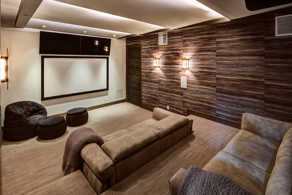 Large modern enclosed home theatre in Salt Lake City with brown walls, a projector screen, carpet and beige floor.