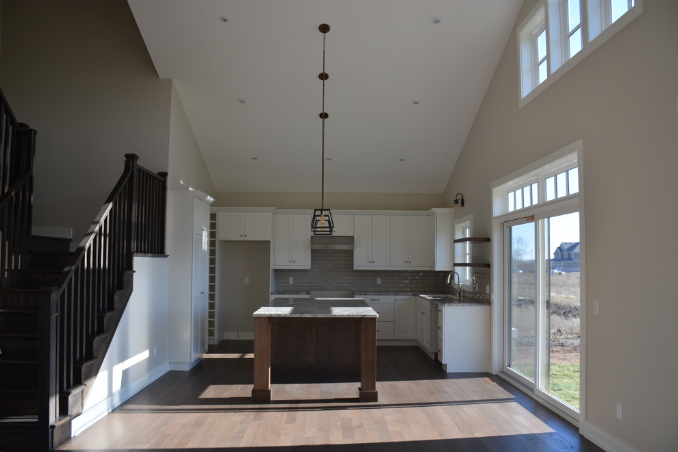 Eat-in kitchen - mid-sized transitional u-shaped light wood floor eat-in kitchen idea in Toronto with a double-bowl sink, shaker cabinets, white cabinets, granite countertops, gray backsplash, subway tile backsplash, stainless steel appliances and an island