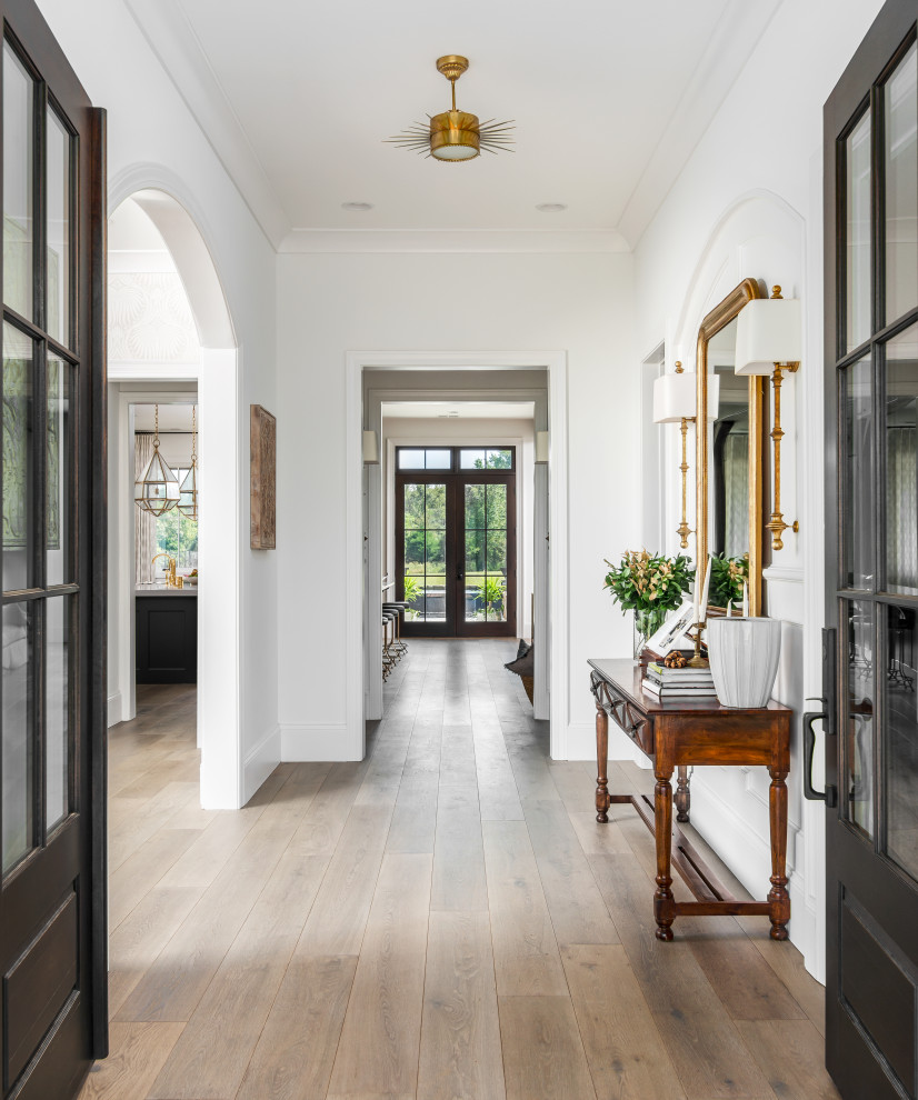This is an example of a large transitional hallway in Nashville with white walls, medium hardwood floors and brown floor.