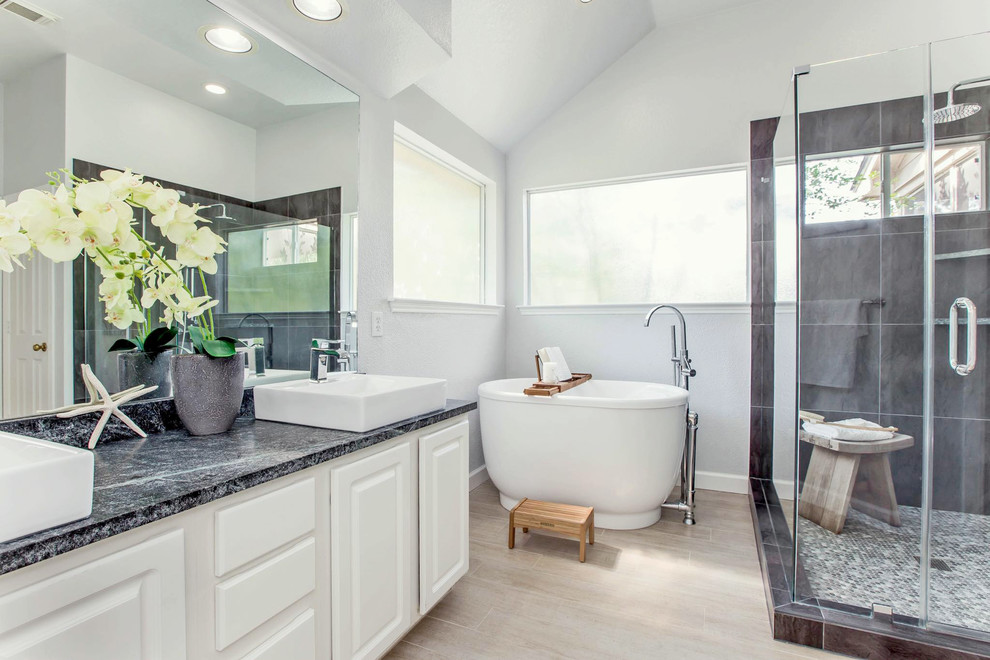 Photo of a traditional ensuite bathroom in Houston with raised-panel cabinets, white cabinets, a freestanding bath, a corner shower, brown tiles, grey walls, a vessel sink and a hinged door.