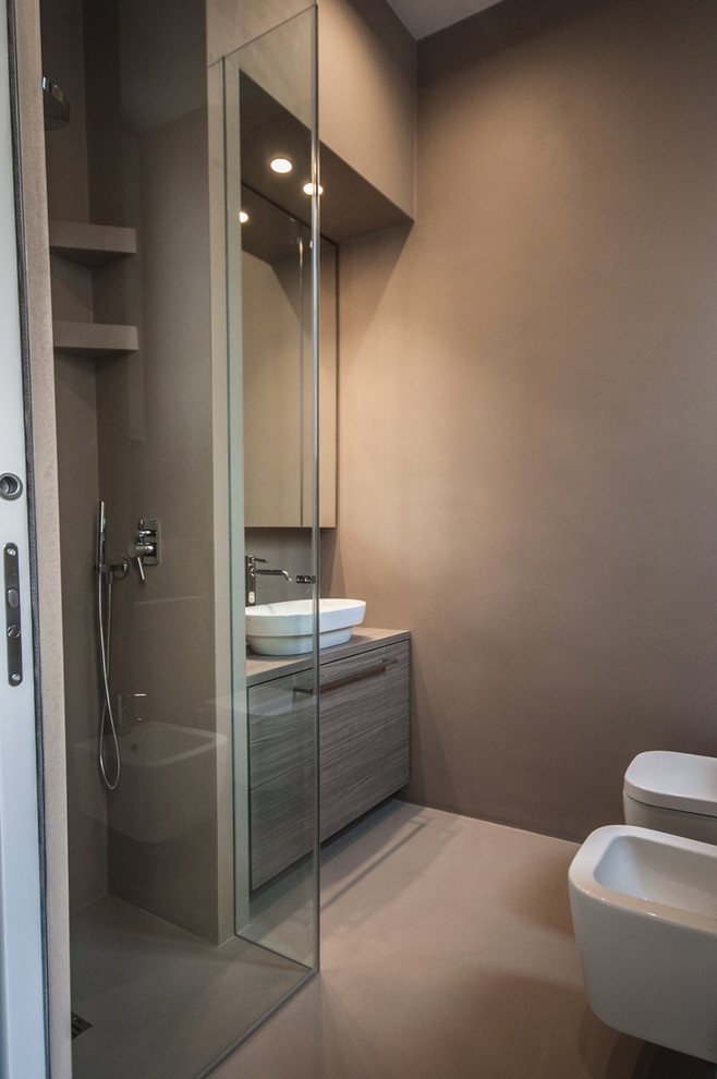 Photo of a small modern 3/4 bathroom in Milan with medium wood cabinets, a curbless shower, a wall-mount toilet, mirror tile, concrete floors, a vessel sink, beige floor and a hinged shower door.