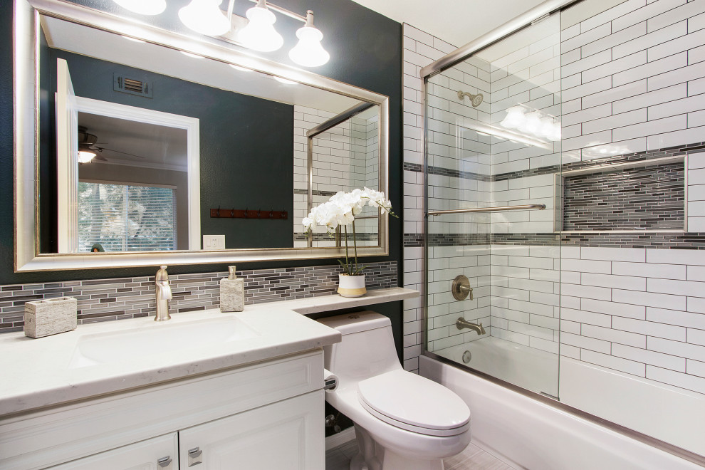 Transitional 3/4 bathroom in Los Angeles with raised-panel cabinets, white cabinets, an alcove tub, a shower/bathtub combo, a one-piece toilet, gray tile, white tile, subway tile, green walls, an integrated sink, grey floor, a hinged shower door and white benchtops.