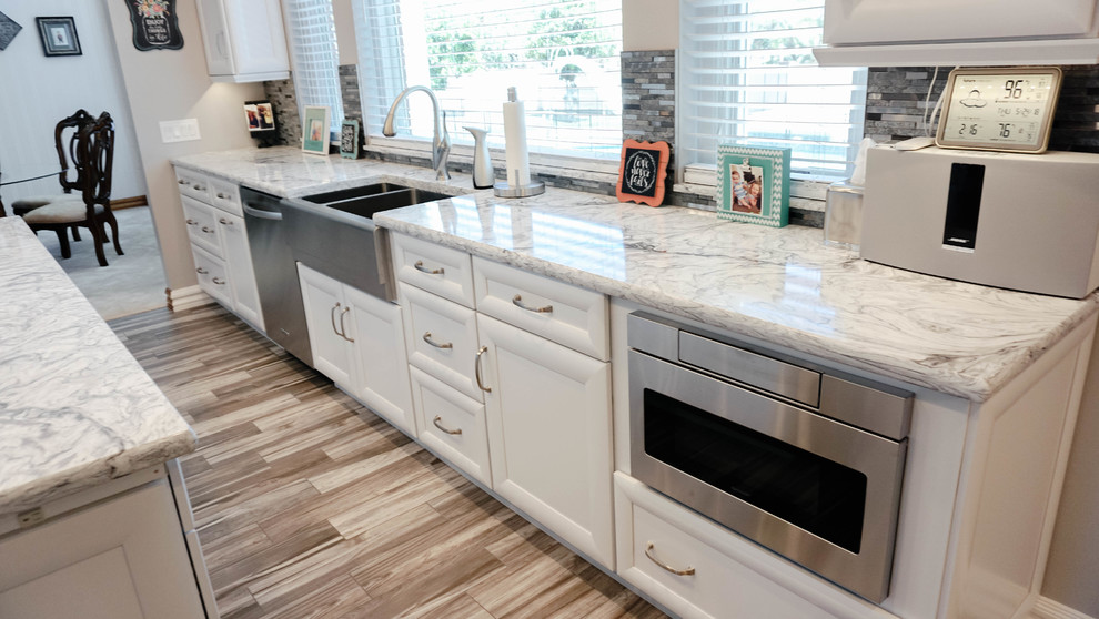 Design ideas for a large modern galley eat-in kitchen in Phoenix with a farmhouse sink, white cabinets, quartzite benchtops, grey splashback, glass tile splashback, stainless steel appliances, porcelain floors, with island, brown floor and white benchtop.