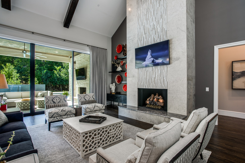 This is an example of a large transitional open concept living room in Dallas with grey walls, medium hardwood floors, a standard fireplace, a stone fireplace surround, a wall-mounted tv, brown floor and vaulted.