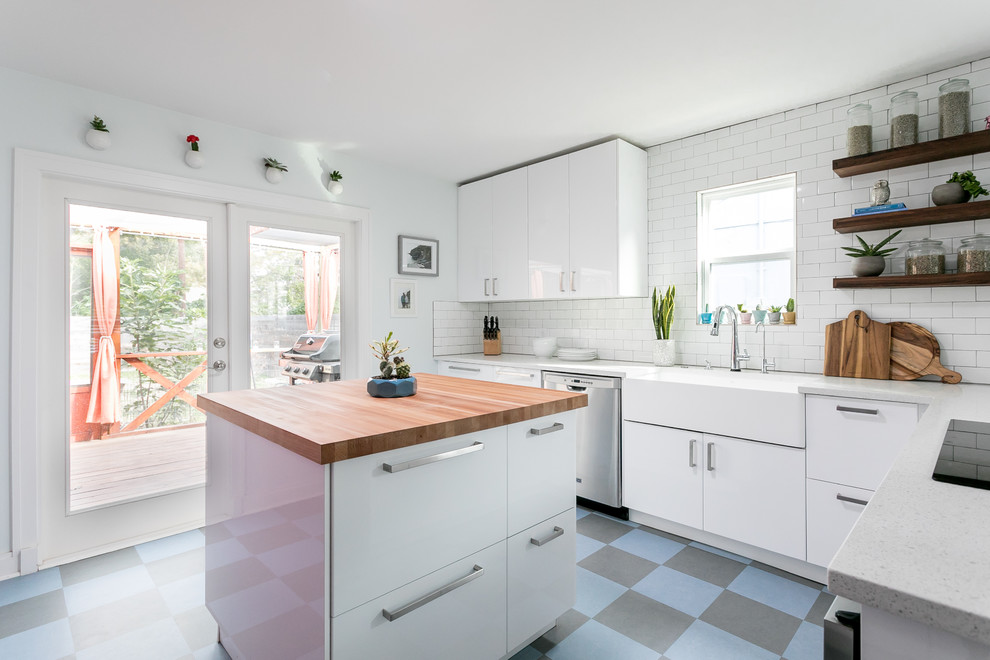 Contemporary u-shaped kitchen in Austin with a farmhouse sink, flat-panel cabinets, white cabinets, white splashback, subway tile splashback, stainless steel appliances, with island and blue floor.