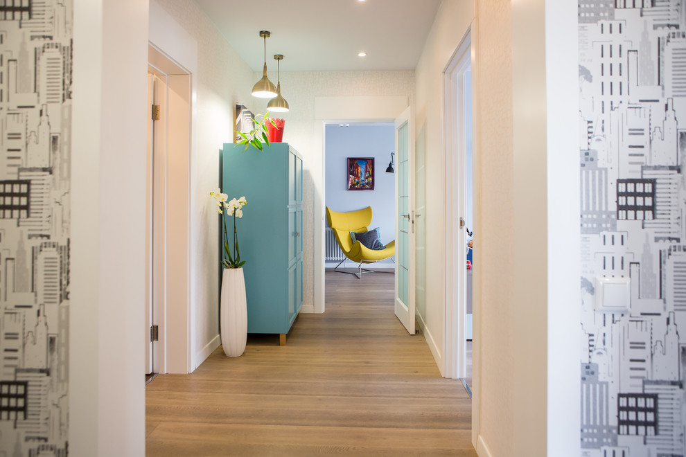 This is an example of a contemporary hallway in Moscow with white walls and light hardwood floors.