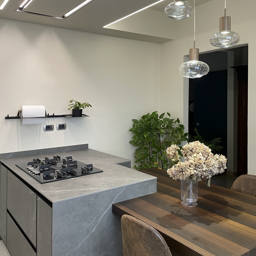 Medium sized contemporary single-wall open plan kitchen in Milan with an integrated sink, flat-panel cabinets, medium wood cabinets, marble worktops, grey splashback, marble splashback, black appliances, porcelain flooring, an island, beige floors, grey worktops and a drop ceiling.