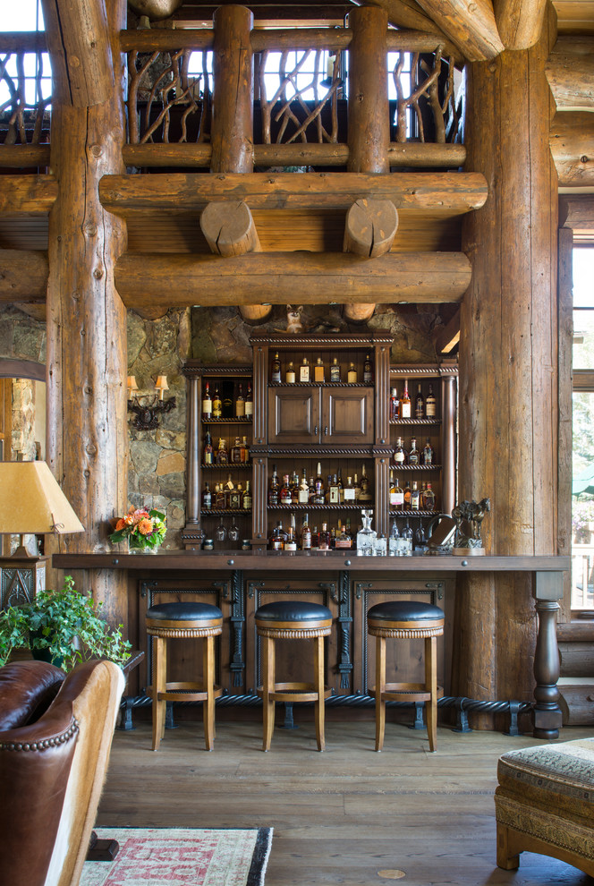 This is an example of a small country seated home bar in Denver with open cabinets, dark wood cabinets and medium hardwood floors.