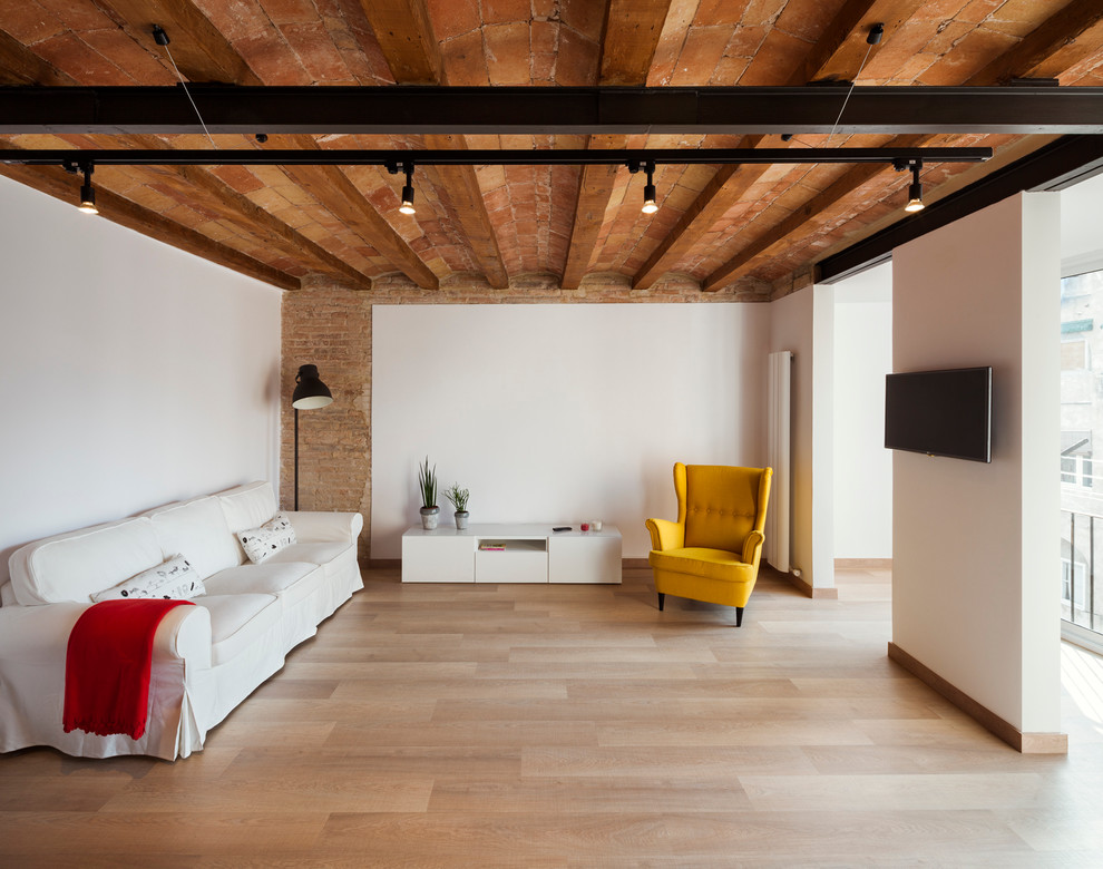 This is an example of a mid-sized industrial formal enclosed living room in Barcelona with white walls, light hardwood floors, no fireplace and a wall-mounted tv.