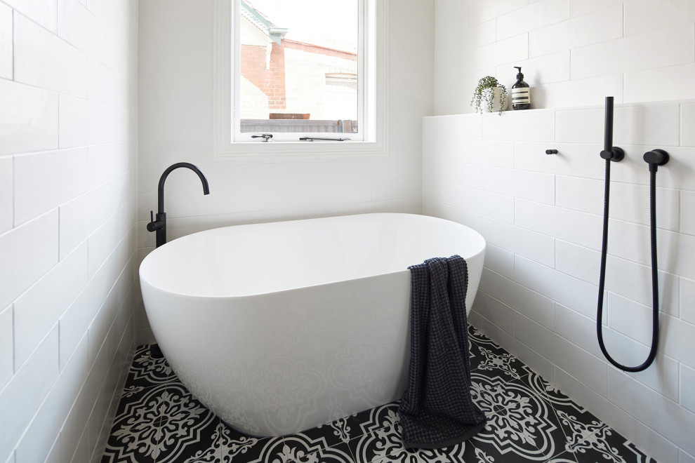 Small traditional 3/4 wet room bathroom in Melbourne with black cabinets, a freestanding tub, a wall-mount toilet, white tile, subway tile, white walls, mosaic tile floors, an undermount sink, laminate benchtops, multi-coloured floor, an open shower, white benchtops and furniture-like cabinets.