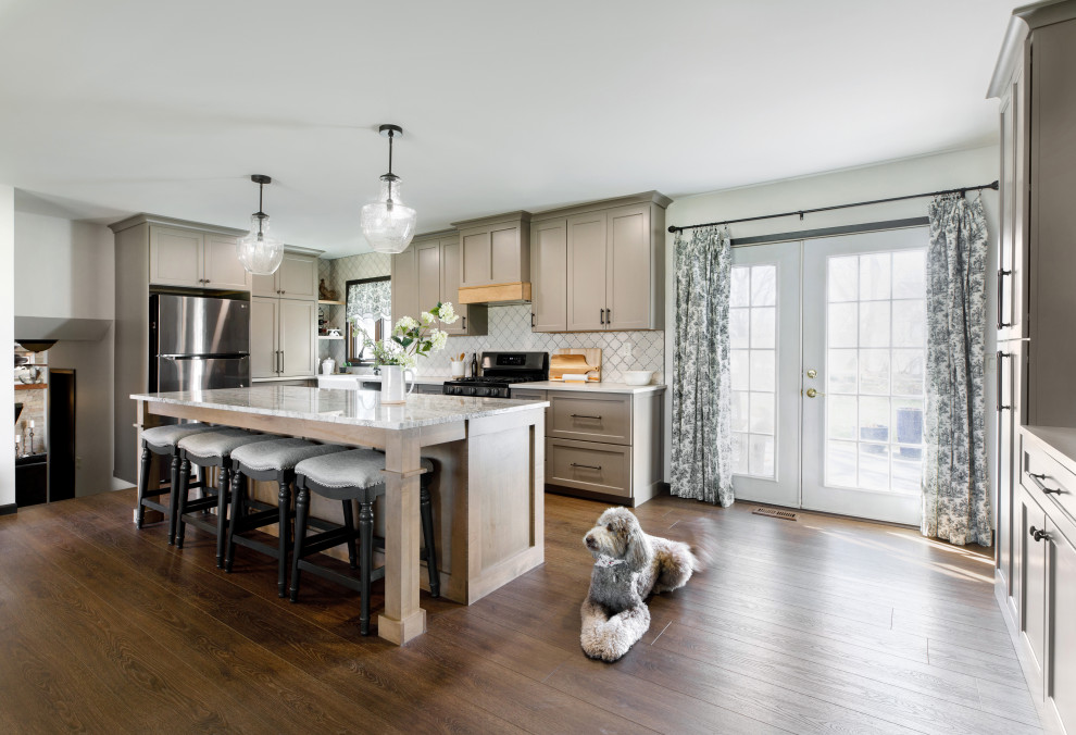 Inspiration for a mid-sized transitional u-shaped eat-in kitchen in Wichita with a farmhouse sink, beaded inset cabinets, grey cabinets, marble benchtops, beige splashback, ceramic splashback, stainless steel appliances, vinyl floors, with island, brown floor and white benchtop.