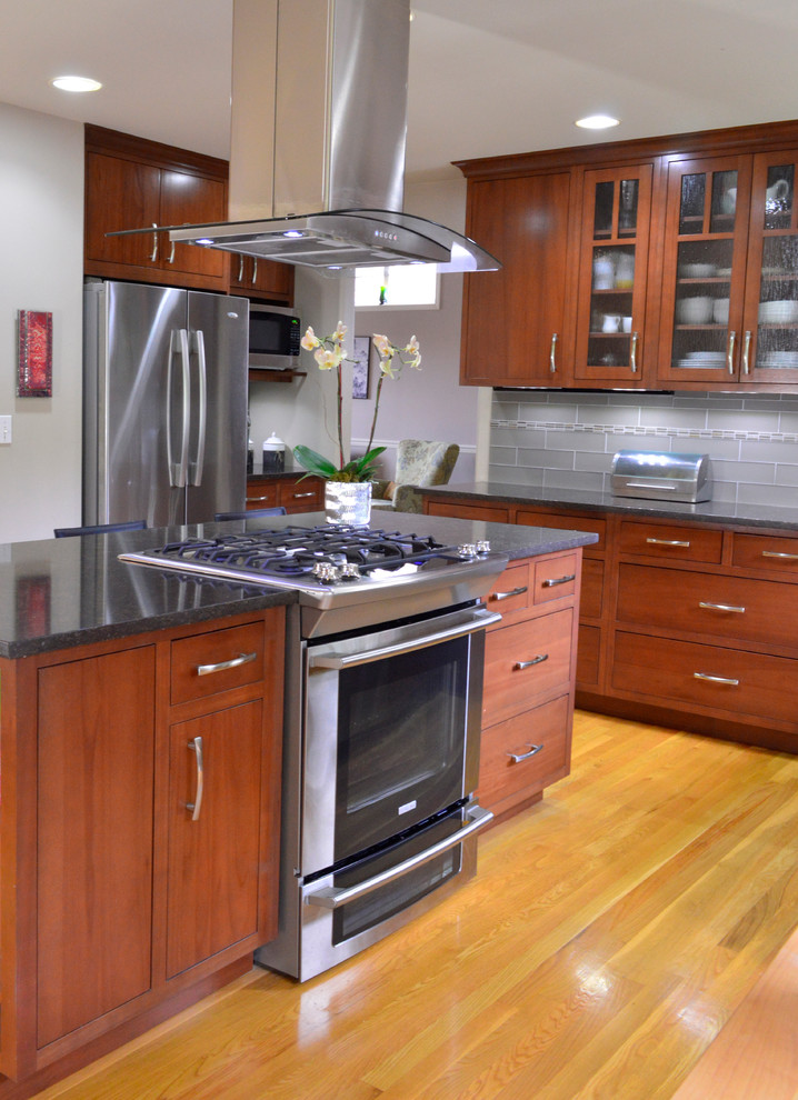 Large transitional medium tone wood floor open concept kitchen photo in Seattle with an undermount sink, flat-panel cabinets, dark wood cabinets, quartz countertops, gray backsplash, subway tile backsplash, stainless steel appliances and an island