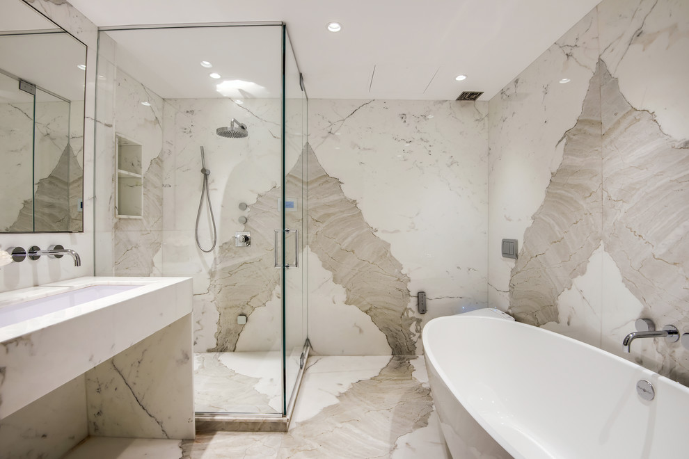 Inspiration for a mid-sized contemporary master bathroom in New York with a freestanding tub, a corner shower, marble, white walls, marble floors, a trough sink, marble benchtops, white floor, a hinged shower door and white benchtops.