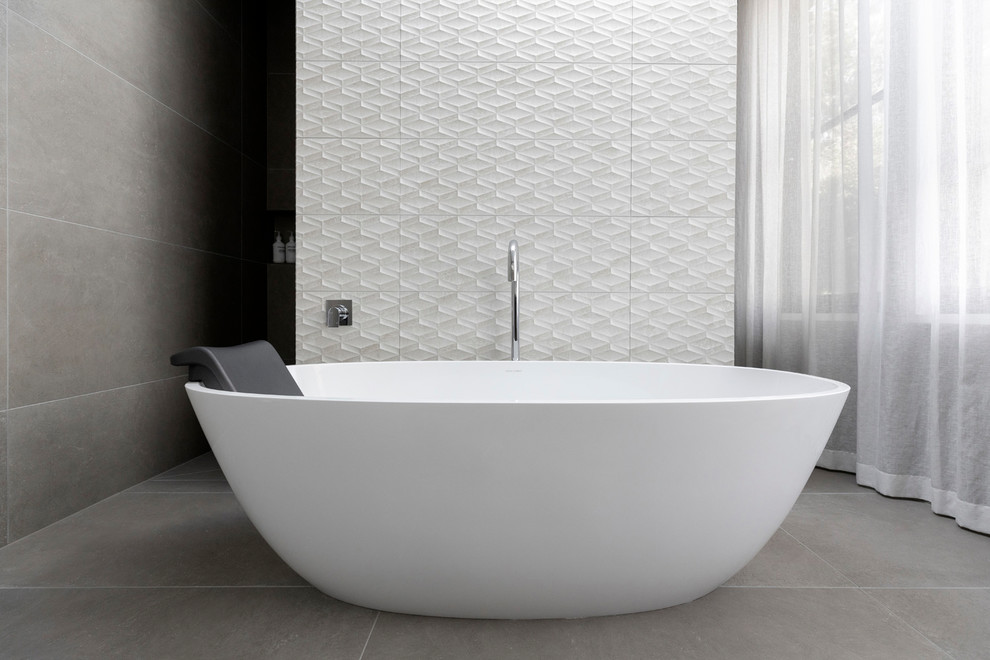 Inspiration for a contemporary master bathroom in Melbourne with a freestanding tub, gray tile, grey walls and grey floor.