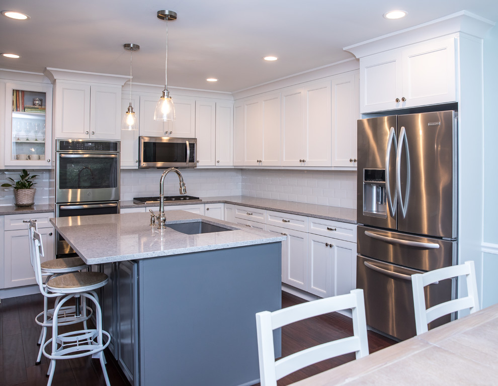 Example of a mid-sized transitional l-shaped brown floor eat-in kitchen design in Atlanta with an undermount sink, white cabinets, quartzite countertops, white backsplash, subway tile backsplash, stainless steel appliances, an island and gray countertops