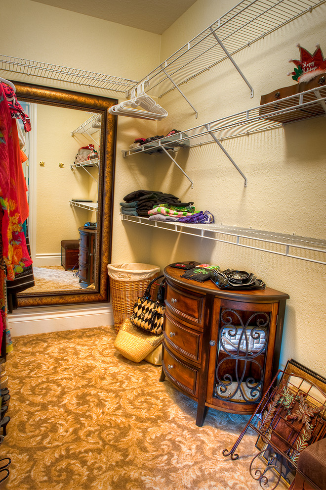 This is an example of a mid-sized traditional gender-neutral walk-in wardrobe in Miami with carpet.