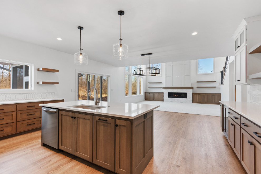 This is an example of a mid-sized transitional u-shaped eat-in kitchen in Other with an undermount sink, shaker cabinets, light wood cabinets, quartz benchtops, white splashback, ceramic splashback, stainless steel appliances, light hardwood floors, with island, brown floor and white benchtop.