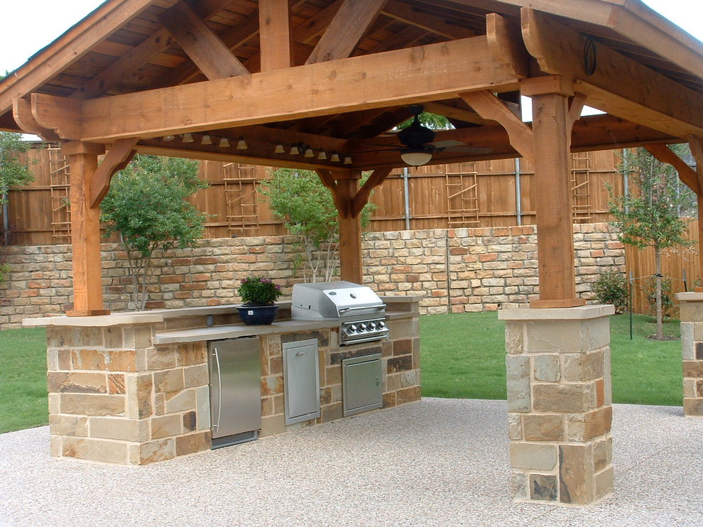 This is an example of a mid-sized country backyard patio in Tampa with an outdoor kitchen and stamped concrete.
