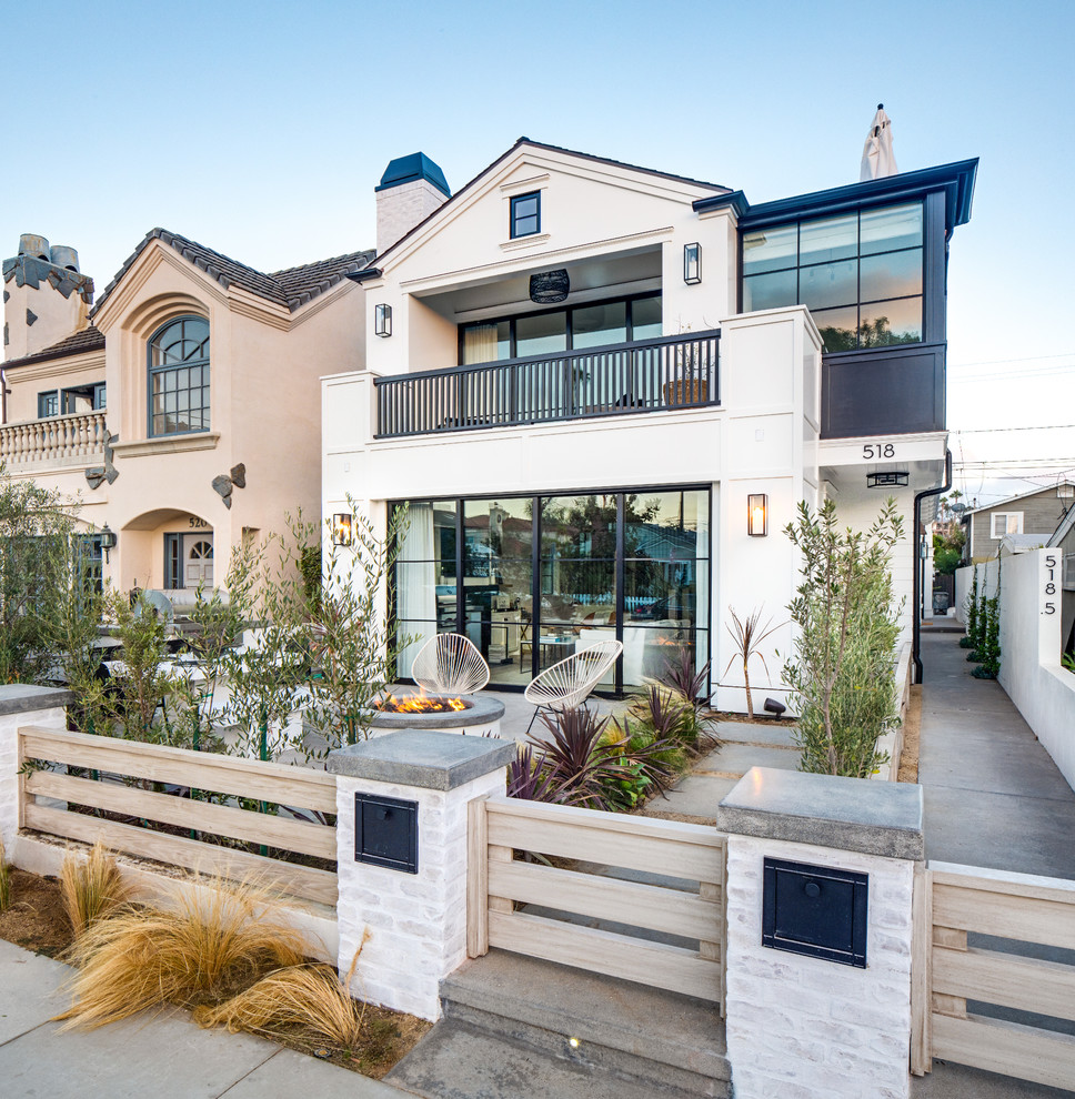 This is an example of a beach style two-storey white house exterior in Los Angeles with a gable roof.