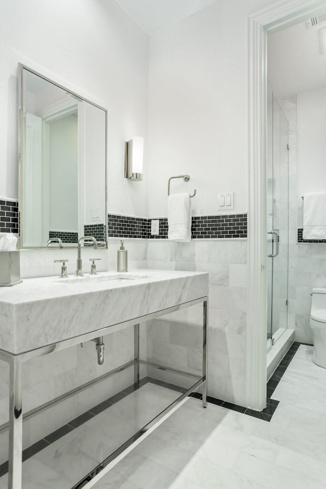 Inredning av ett klassiskt litet grå grått badrum med dusch, med möbel-liknande, grå skåp, en dusch i en alkov, en toalettstol med hel cisternkåpa, svart och vit kakel, marmorkakel, vita väggar, marmorgolv, ett undermonterad handfat, marmorbänkskiva, grått golv och dusch med gångjärnsdörr