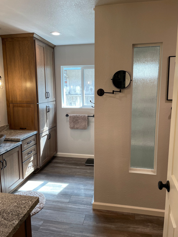 This is an example of a mid-sized transitional master bathroom in Other with shaker cabinets, medium wood cabinets, a double shower, a two-piece toilet, gray tile, porcelain tile, beige walls, wood-look tile, a vessel sink, granite benchtops, brown floor, a hinged shower door, grey benchtops, a shower seat, a double vanity and a built-in vanity.