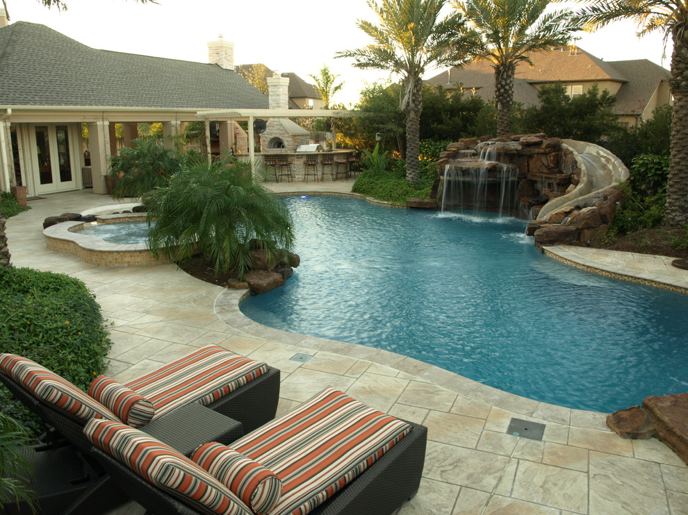 Large tropical backyard custom-shaped lap pool in Houston with a water slide and tile.