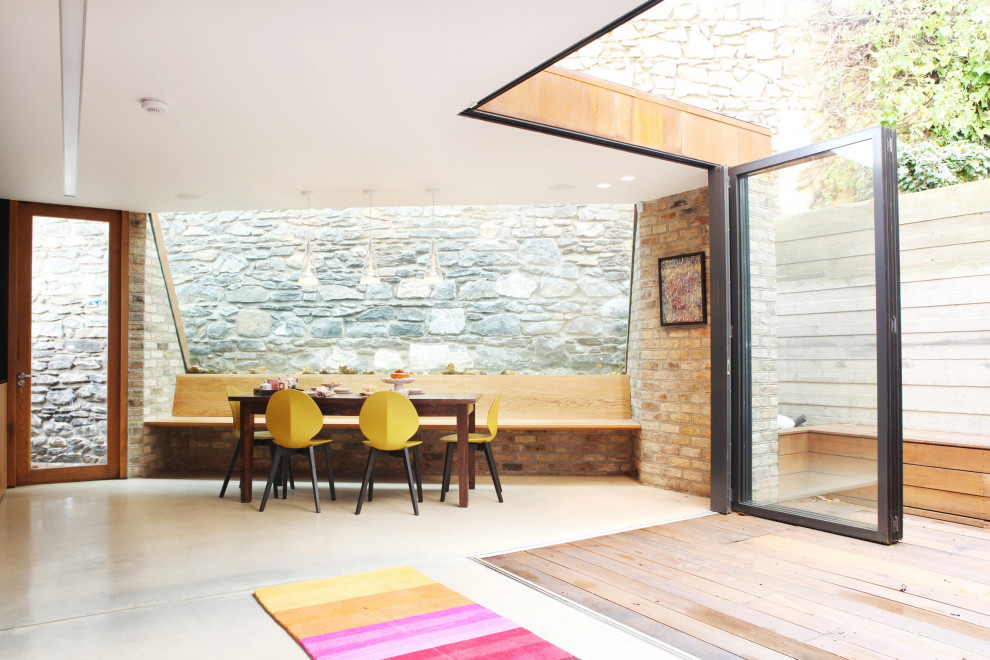 Пример оригинального дизайна: гостиная-столовая в современном стиле с бежевыми стенами, бетонным полом, серым полом и кирпичными стенами