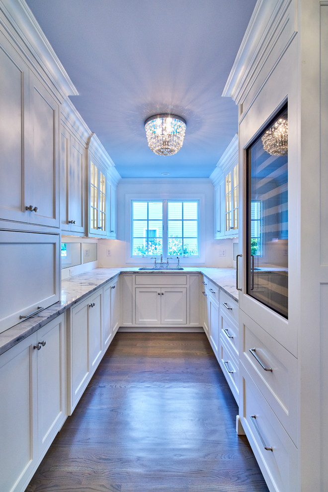 This is an example of a traditional u-shaped kitchen in New York with recessed-panel cabinets, white cabinets, dark hardwood floors and no island.