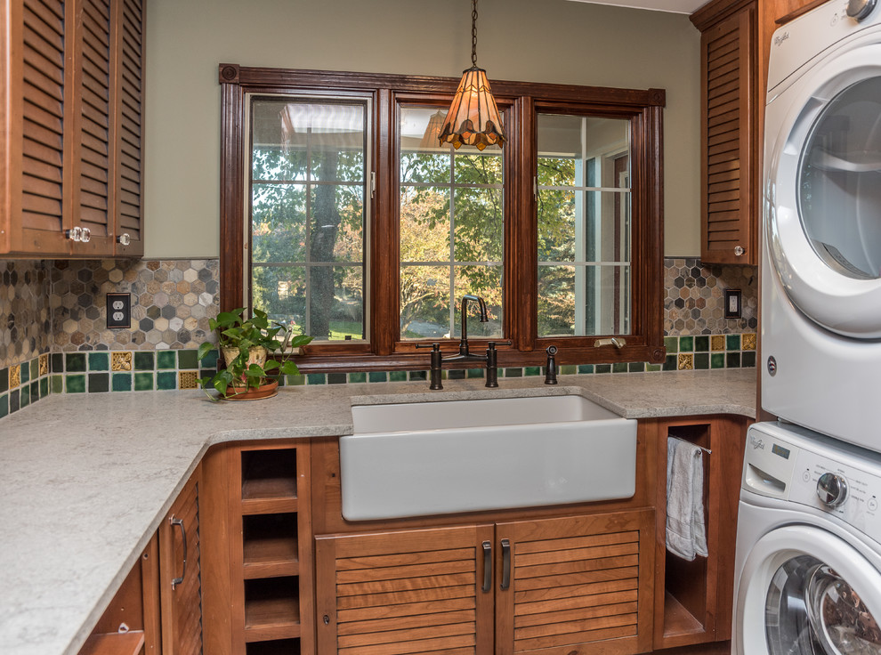 Photo of a large arts and crafts u-shaped utility room in Detroit with a farmhouse sink, open cabinets, distressed cabinets, quartz benchtops, green walls, slate floors, a stacked washer and dryer, multi-coloured floor and multi-coloured benchtop.
