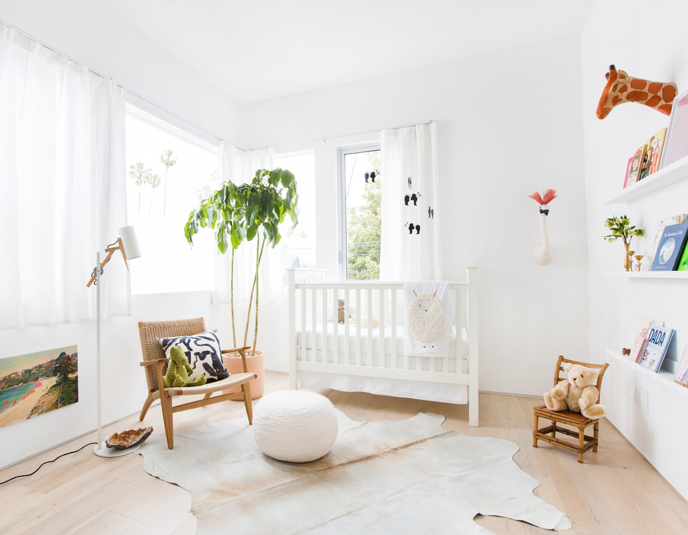 Mid-sized modern nursery in Los Angeles with white walls, light hardwood floors and beige floor for girls.