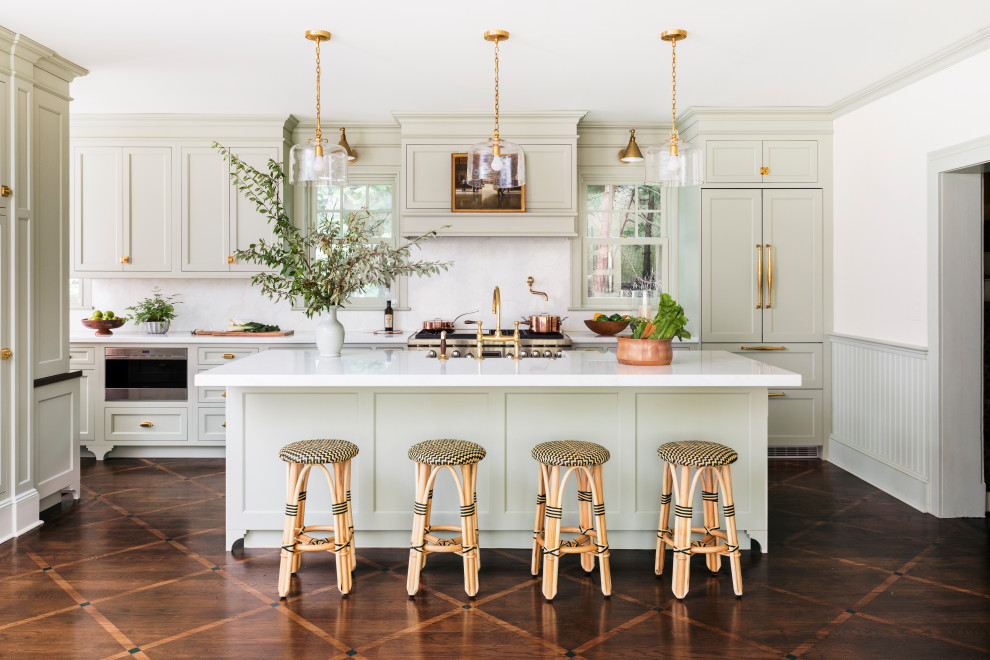 Inspiration for a large traditional single-wall eat-in kitchen in New York with a farmhouse sink, recessed-panel cabinets, beige cabinets, marble benchtops, white splashback, marble splashback, stainless steel appliances, dark hardwood floors, with island, brown floor and white benchtop.