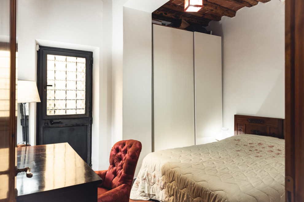 Idee per una piccola camera matrimoniale minimalista con pareti bianche, pavimento in terracotta, pavimento rosso, travi a vista e abbinamento di mobili antichi e moderni