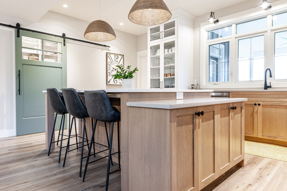 Example of a mid-sized transitional l-shaped laminate floor and brown floor eat-in kitchen design in Toronto with an undermount sink, recessed-panel cabinets, white cabinets, quartz countertops, stainless steel appliances, an island and white countertops